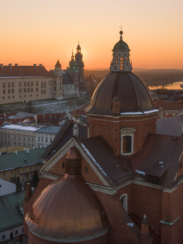 Wieża kościoła, a w tle Wawel. Zdjęcie z drona o zachodzie słońca.
